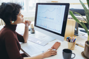 person at a work desk studying something on a pc monitor