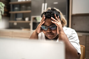 person looking at laptop screen with head in hands