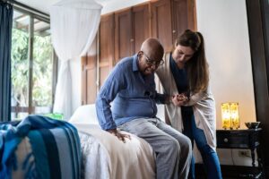 Nurse helping elderly man from bed in nursing home. suecVCJ