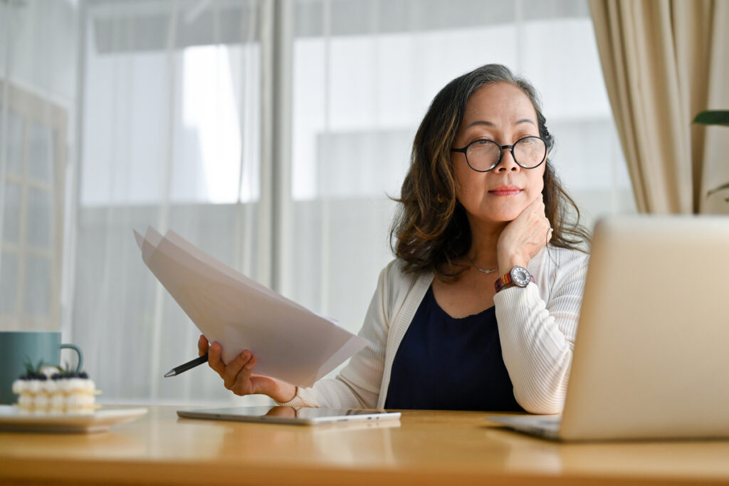 senior holding documents and looking at computer