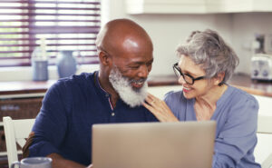 smiling mature couple using laptop at home