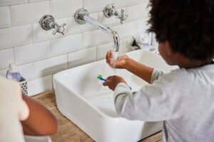 young children brushing teeth at sink