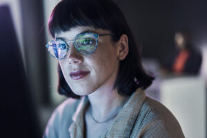 a business person looking at charts on a computer with light reflecting off their glasses