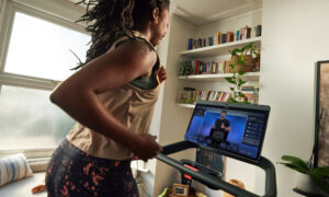 person using peloton treadmill while peloton instructor is in view on screen peloton