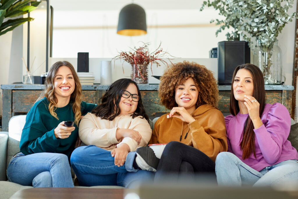 four people sitting on a couch watching streaming