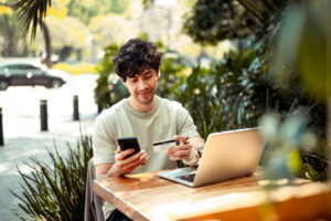 25 03 27 a person using a credit card while holding a phone and sitting in front of a computer mf dload gettyimages 1305615921 1200x798 36b7a2e