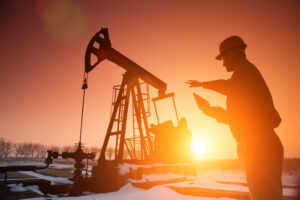 a person working near an oil pump with the sun setting in the background