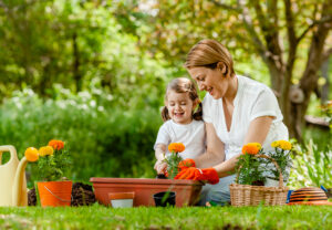 elder person planting flowers with their grandchild